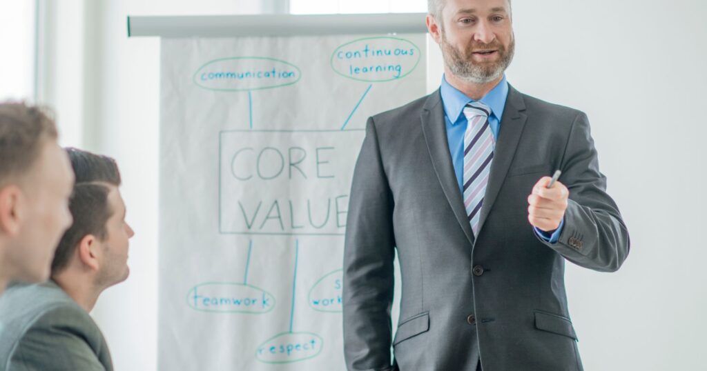 A man in a suit presents to colleagues. They discuss 'Navigating Ethical and Practical Challenges'.