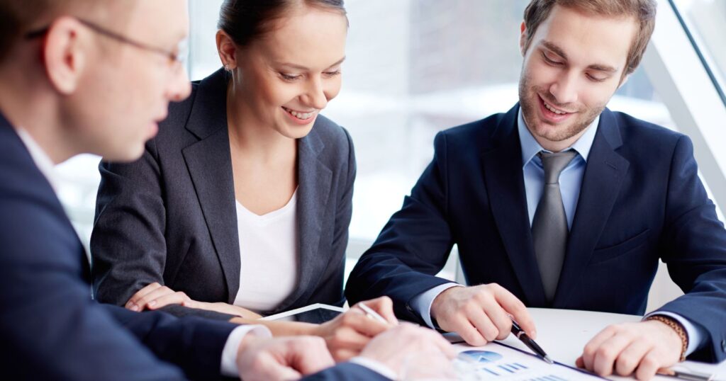 Three professionals discussing documents at a table. Positive Aspects Highlighted by Google.