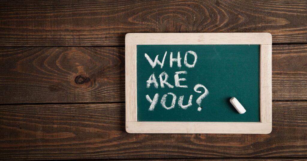 "Who are you?" written on a blackboard on a wooden table - a thought-provoking image about self-identity and social media branding.