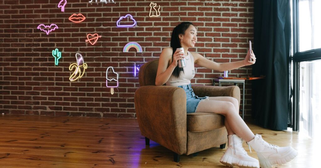 A woman sitting on a chair in a room adorned with vibrant neon signs on the wall.