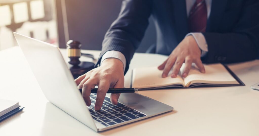 A professional man in a suit is diligently typing on a laptop, engaged in Law Firm Workflows.