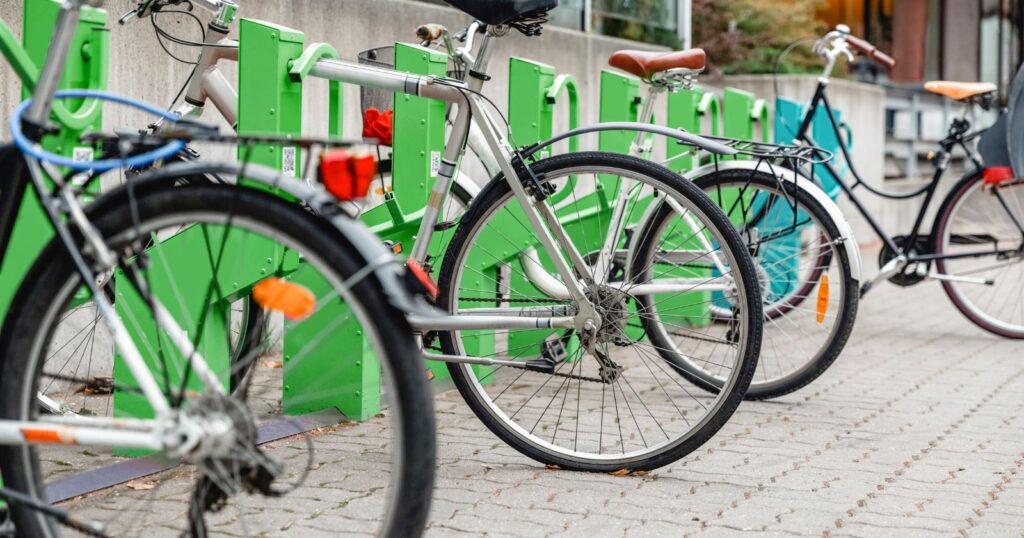 Bikes parked in front of green and white bike racks, promoting Sustainable Transportation.